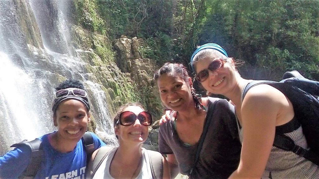 four women standing in front of a waterfall