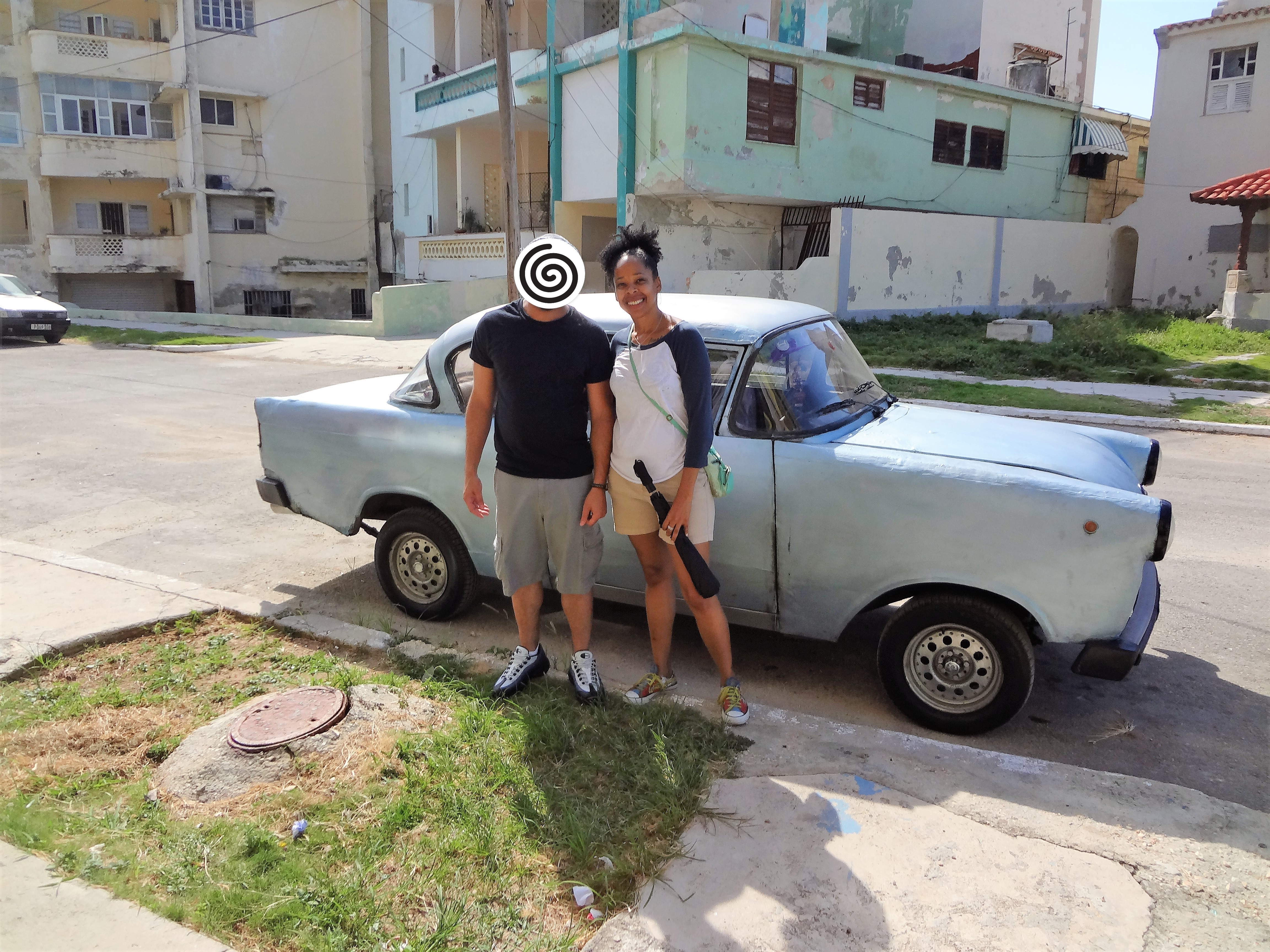 Couple in front of car on street in Cuba