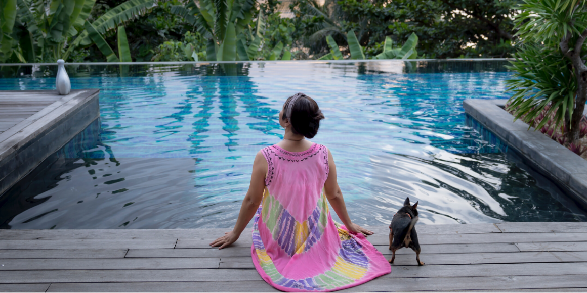 woman and dog sitting near pool