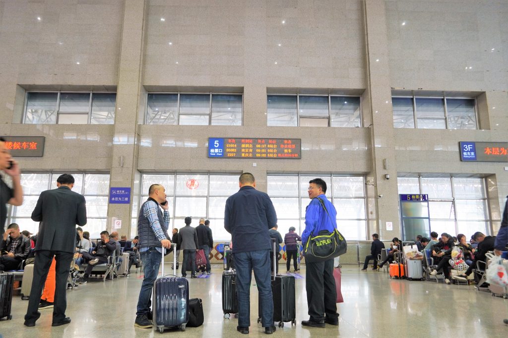 men standing in train station with their luggage